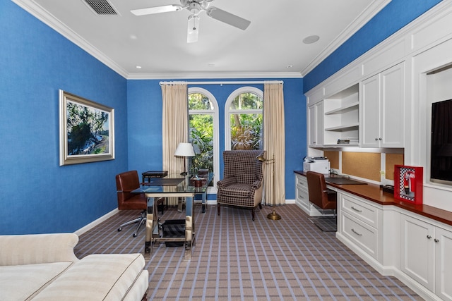 carpeted home office with built in desk, ceiling fan, and crown molding