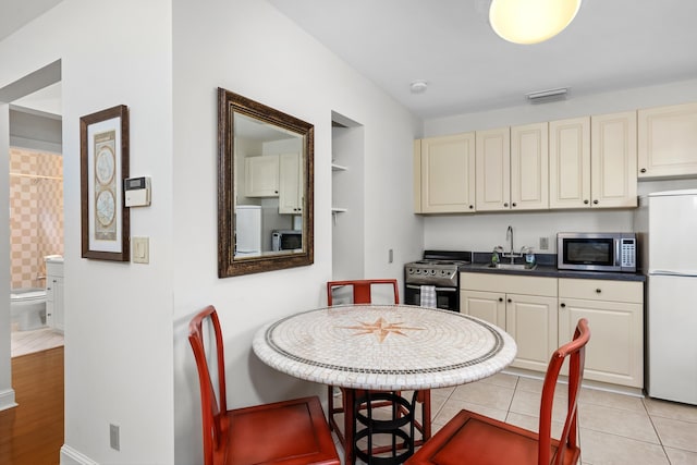 kitchen featuring white refrigerator, sink, light tile patterned floors, range, and built in shelves