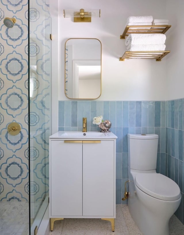 bathroom featuring a shower, vanity, toilet, and tile walls