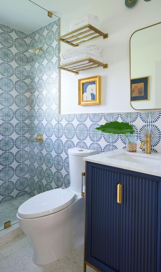 bathroom featuring walk in shower, vanity, toilet, and tile walls