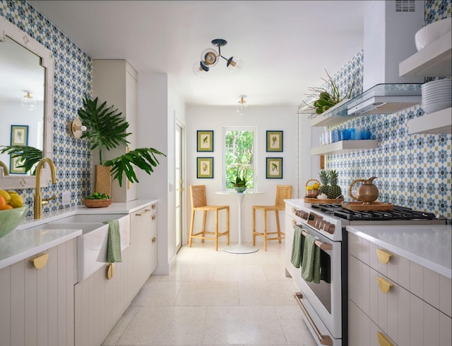 kitchen with backsplash, ventilation hood, sink, high end stove, and white cabinetry