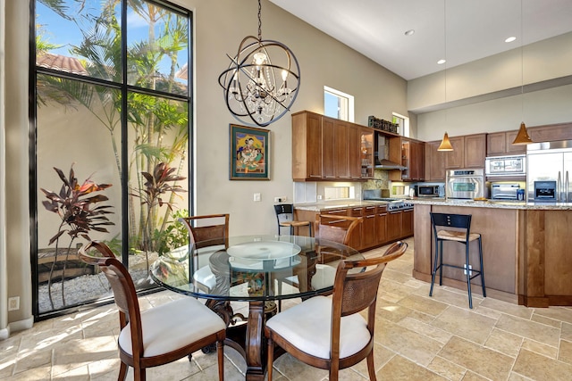 dining area featuring a towering ceiling, a wealth of natural light, and a notable chandelier