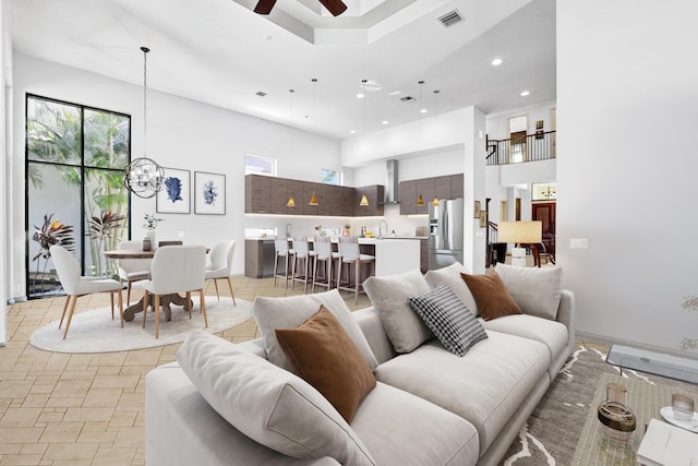 living room featuring a high ceiling, ceiling fan, and sink