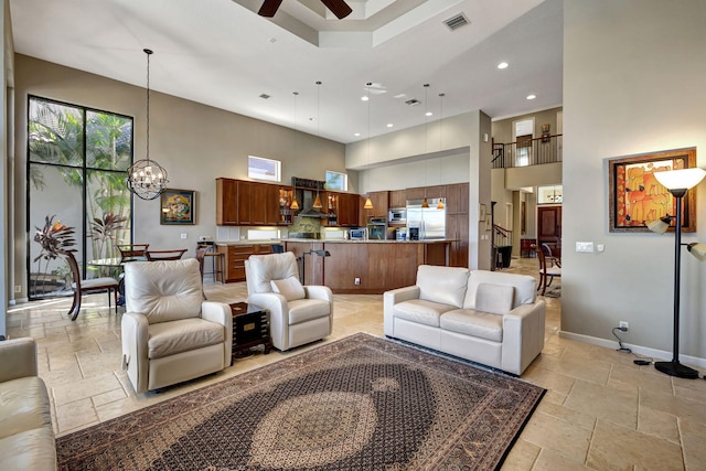 living room with a towering ceiling and ceiling fan with notable chandelier