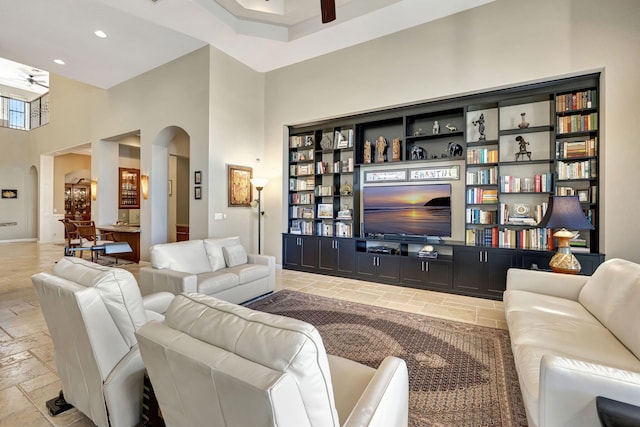 living room with ceiling fan and a high ceiling