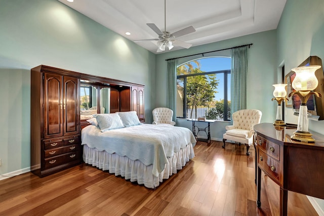 bedroom featuring hardwood / wood-style floors, ceiling fan, and a tray ceiling