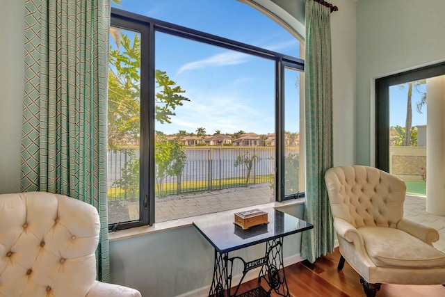 sitting room with hardwood / wood-style flooring and a water view