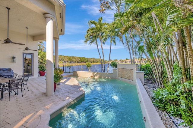 view of swimming pool with pool water feature, a water view, a patio, and ceiling fan