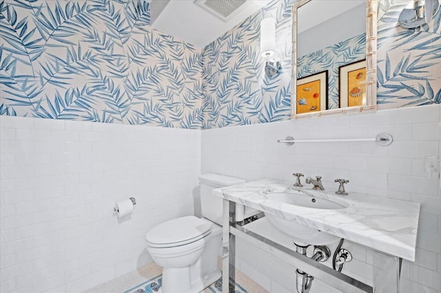 bathroom featuring sink, tile walls, and toilet