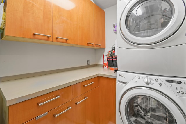 washroom with cabinets and stacked washing maching and dryer