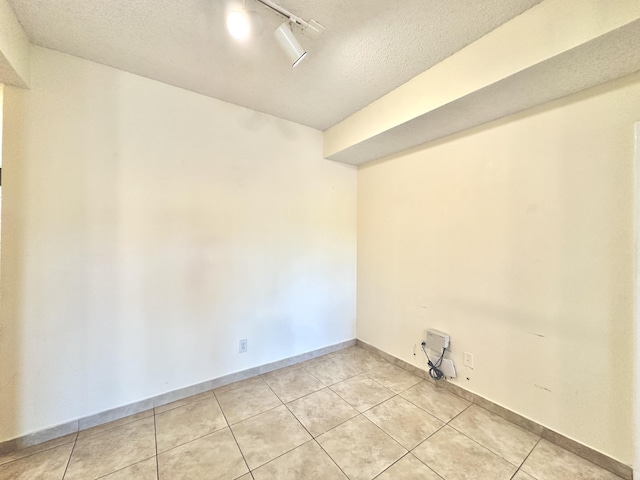 tiled spare room with a textured ceiling and rail lighting