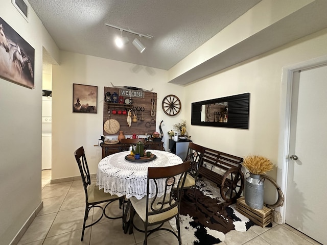 tiled dining space with a textured ceiling and track lighting