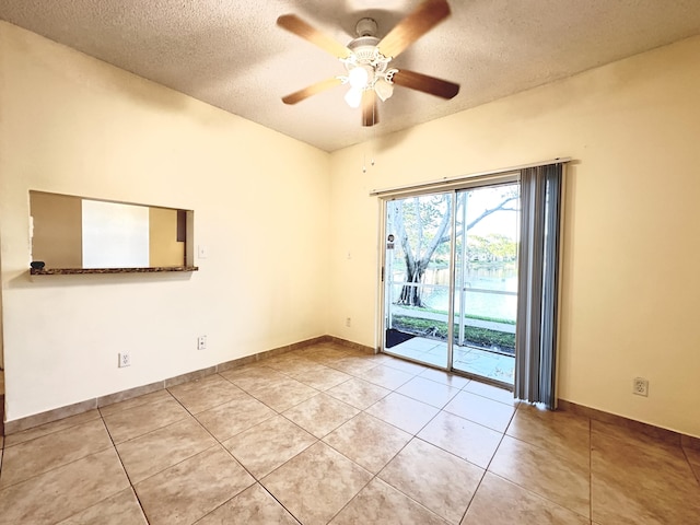 tiled empty room featuring a textured ceiling and ceiling fan