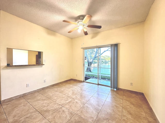 spare room with ceiling fan, light tile patterned floors, and a textured ceiling