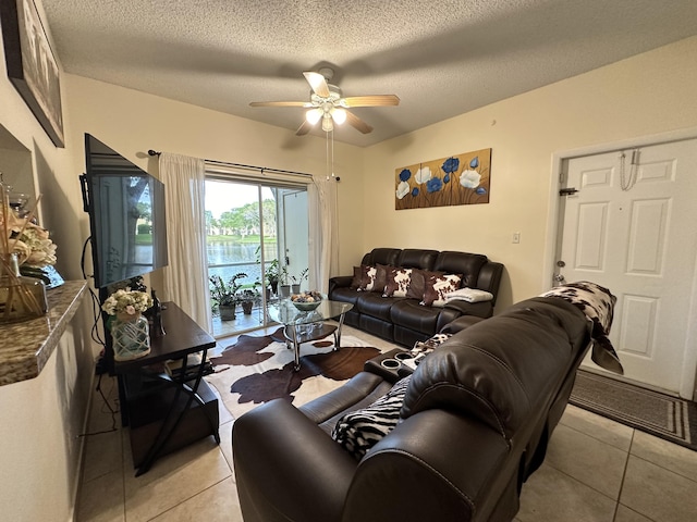 living room featuring ceiling fan, light tile patterned flooring, and a textured ceiling