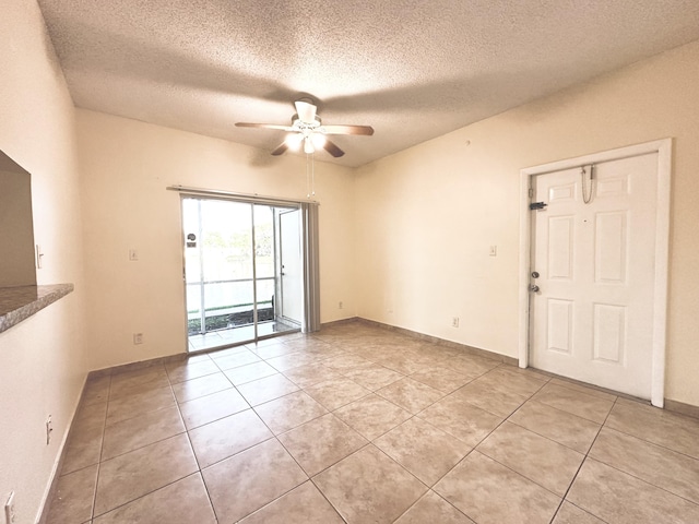 spare room featuring ceiling fan, light tile patterned flooring, and a textured ceiling