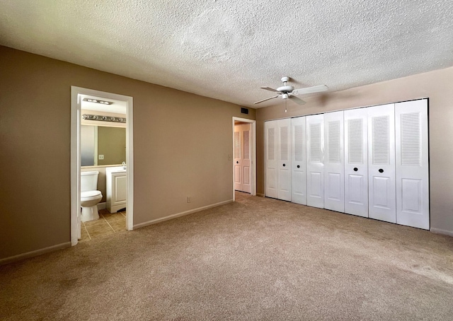 unfurnished bedroom with ensuite bath, carpet, baseboards, and a textured ceiling