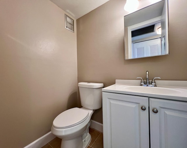 half bathroom with toilet, baseboards, vanity, and tile patterned floors