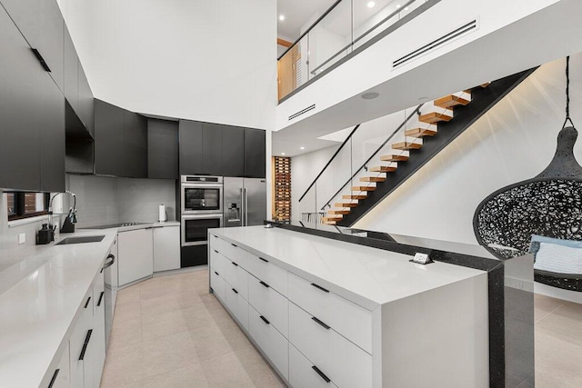 kitchen featuring appliances with stainless steel finishes, sink, light tile patterned floors, white cabinetry, and a large island