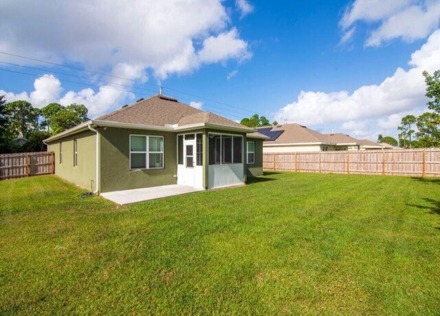 back of property with a lawn and a patio area