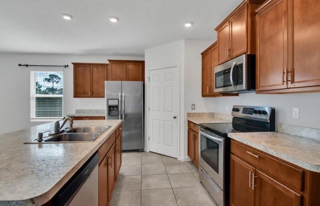 kitchen with sink, light tile patterned floors, a textured ceiling, an island with sink, and appliances with stainless steel finishes