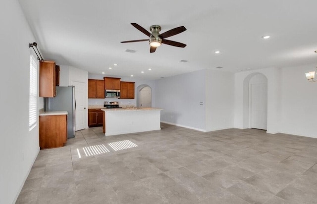 kitchen with ceiling fan with notable chandelier, a center island, and appliances with stainless steel finishes