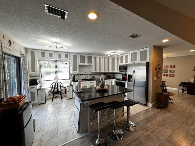 kitchen featuring sink, stainless steel appliances, a textured ceiling, decorative backsplash, and white cabinets