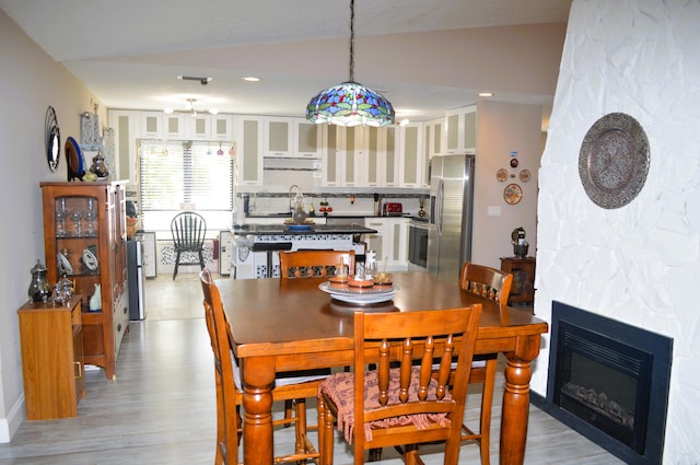 dining area with sink, vaulted ceiling, and light wood-type flooring