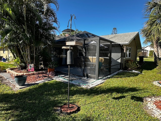 back of house with glass enclosure and a yard