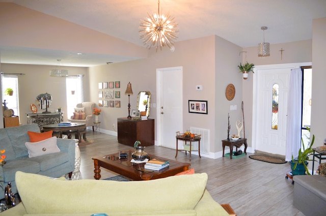 living room with a chandelier, light hardwood / wood-style floors, and lofted ceiling