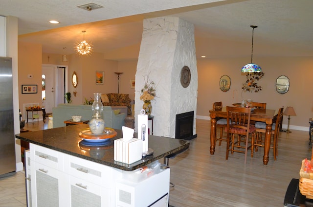 kitchen featuring a fireplace, white cabinets, hanging light fixtures, and a kitchen island