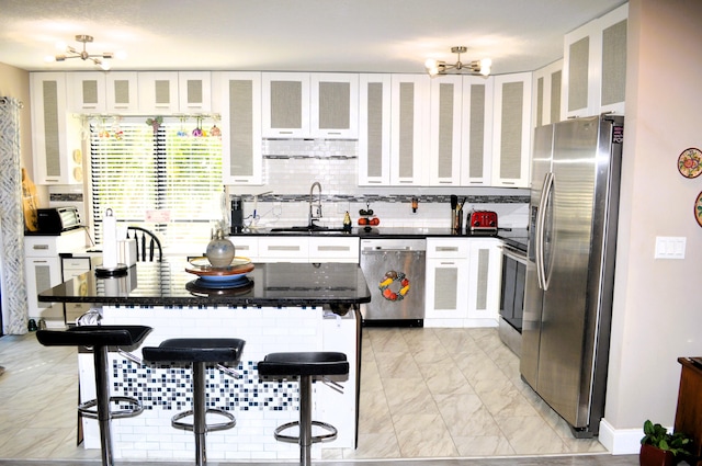 kitchen featuring a kitchen breakfast bar, white cabinetry, sink, and appliances with stainless steel finishes