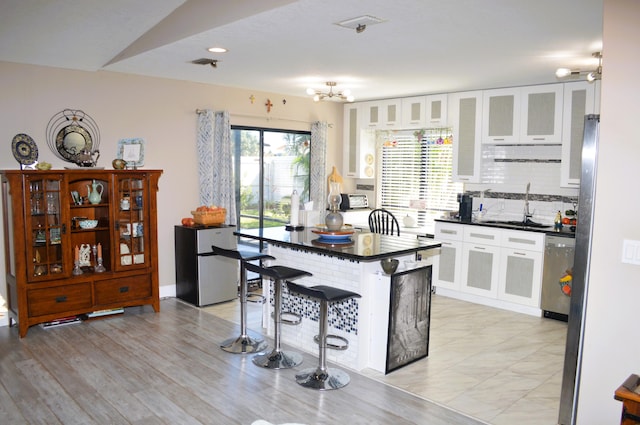 kitchen with white cabinets, a breakfast bar, dishwasher, and sink