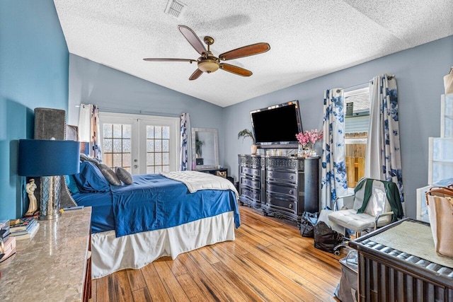 bedroom with hardwood / wood-style flooring, ceiling fan, lofted ceiling, and a textured ceiling