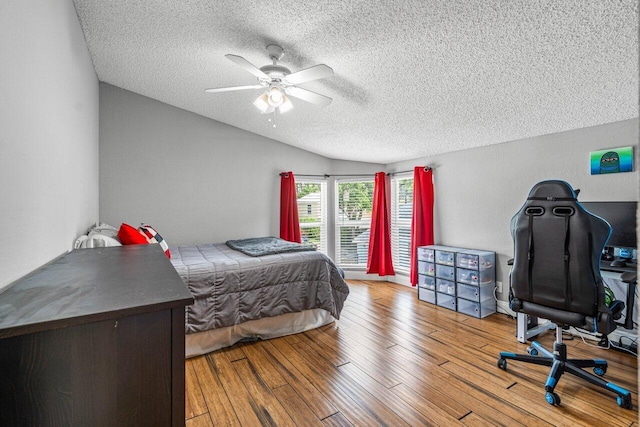 bedroom with a textured ceiling, light hardwood / wood-style floors, vaulted ceiling, and ceiling fan