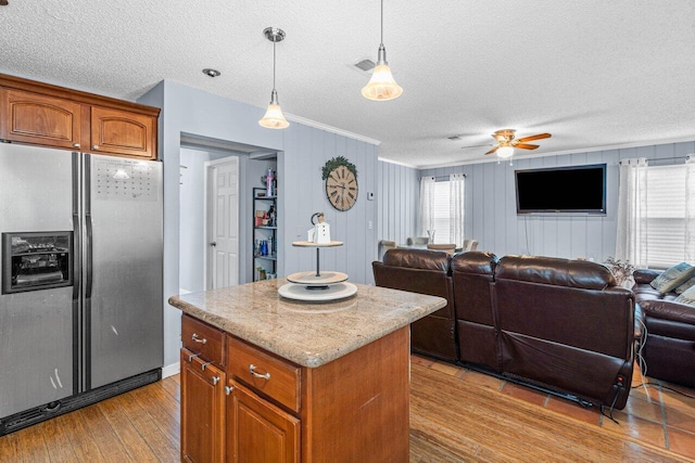 kitchen with light hardwood / wood-style floors, stainless steel fridge, a healthy amount of sunlight, and hanging light fixtures