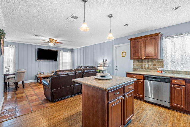 kitchen featuring decorative backsplash, light wood-type flooring, ceiling fan, dishwasher, and a center island