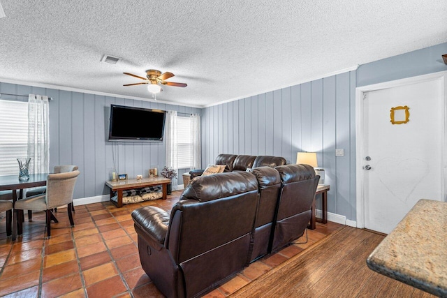 living room featuring ceiling fan, dark hardwood / wood-style flooring, crown molding, a textured ceiling, and wooden walls