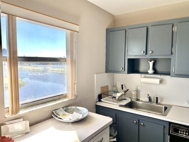 kitchen featuring gray cabinetry, dishwashing machine, and sink