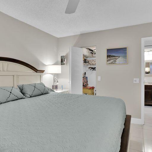 bedroom with ceiling fan, light tile patterned floors, and a textured ceiling