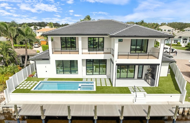 back of house with a lawn, a patio area, a fenced in pool, and a balcony