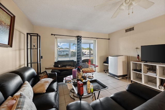 living room with ceiling fan, light tile patterned flooring, and a textured ceiling