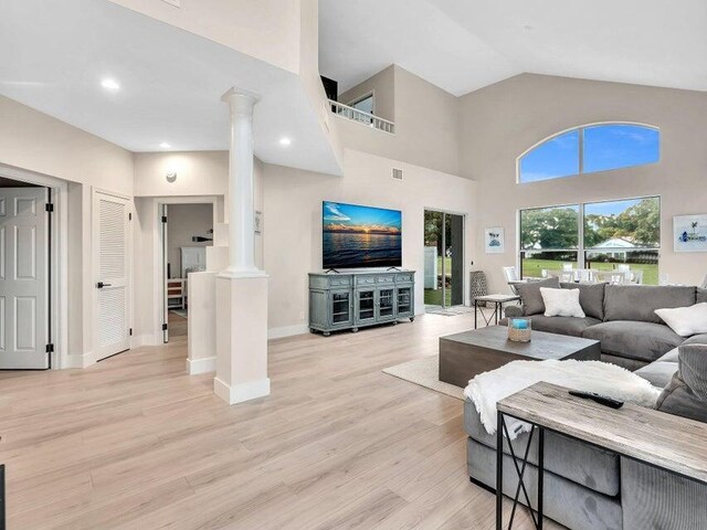 dining space with ceiling fan, light wood-type flooring, and a towering ceiling