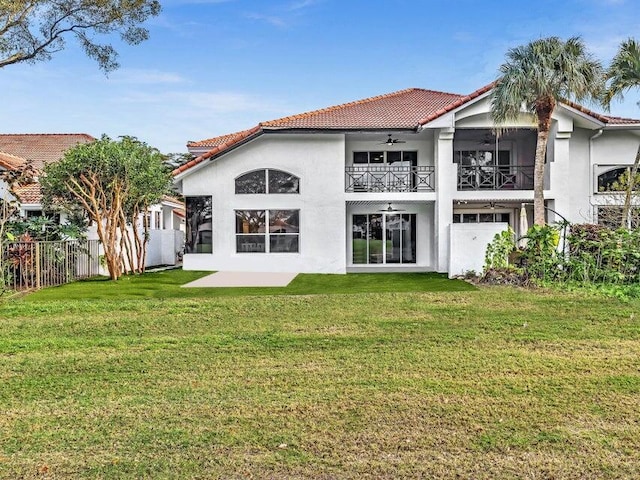 rear view of property featuring a balcony, ceiling fan, and a lawn