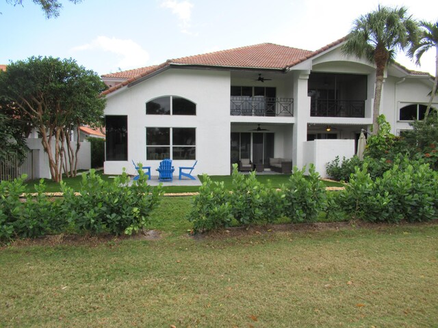 rear view of property featuring a yard, a balcony, and a patio