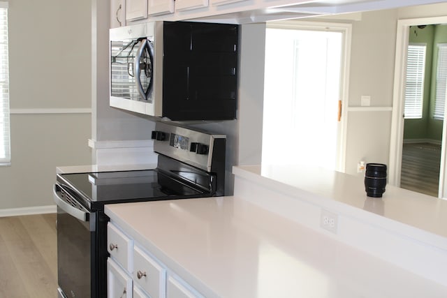 kitchen featuring a healthy amount of sunlight, white cabinetry, stainless steel appliances, and light hardwood / wood-style floors