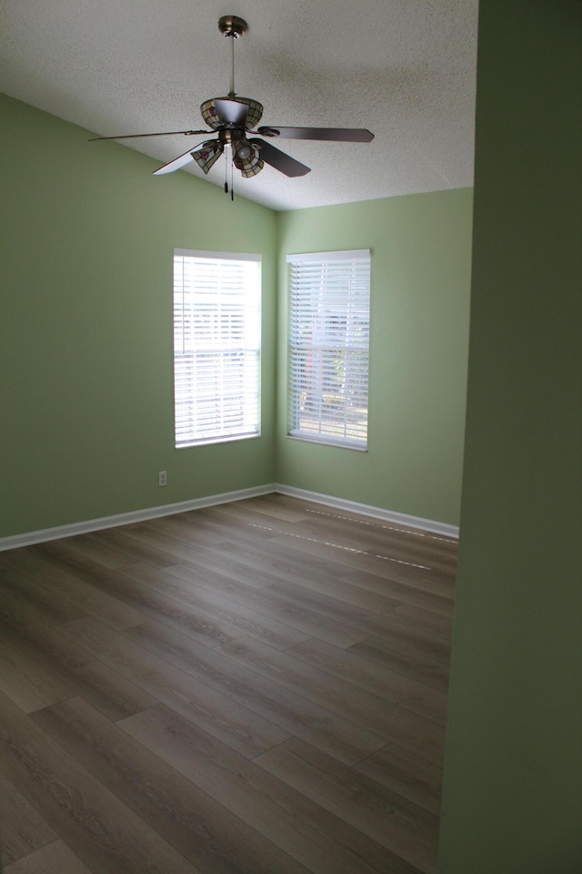 spare room with ceiling fan, dark hardwood / wood-style flooring, a textured ceiling, and vaulted ceiling