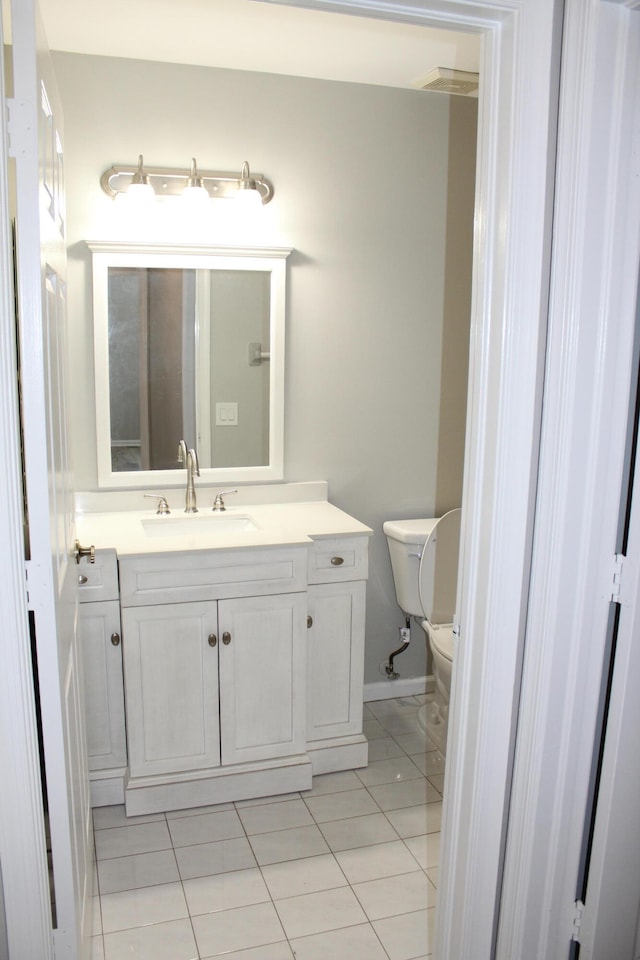 bathroom with toilet, vanity, and tile patterned floors