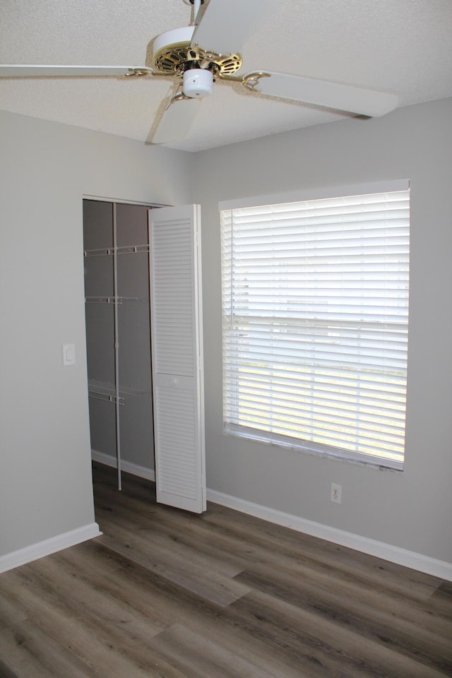 unfurnished bedroom with a closet, ceiling fan, and dark wood-type flooring