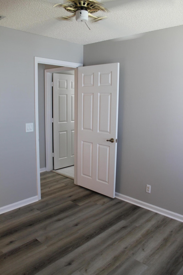 unfurnished bedroom featuring ceiling fan, dark hardwood / wood-style floors, and a textured ceiling